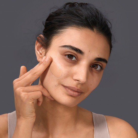 Woman applying foundation on her cheekbone
