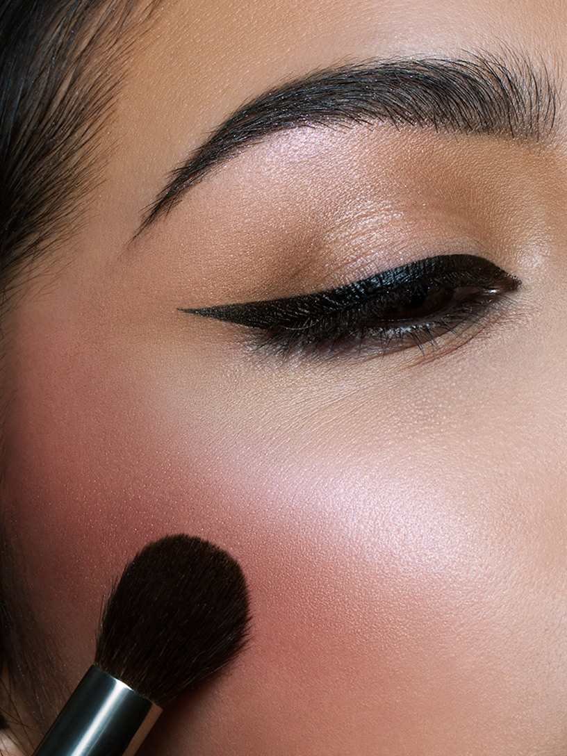 Woman applying blush on cheeks
