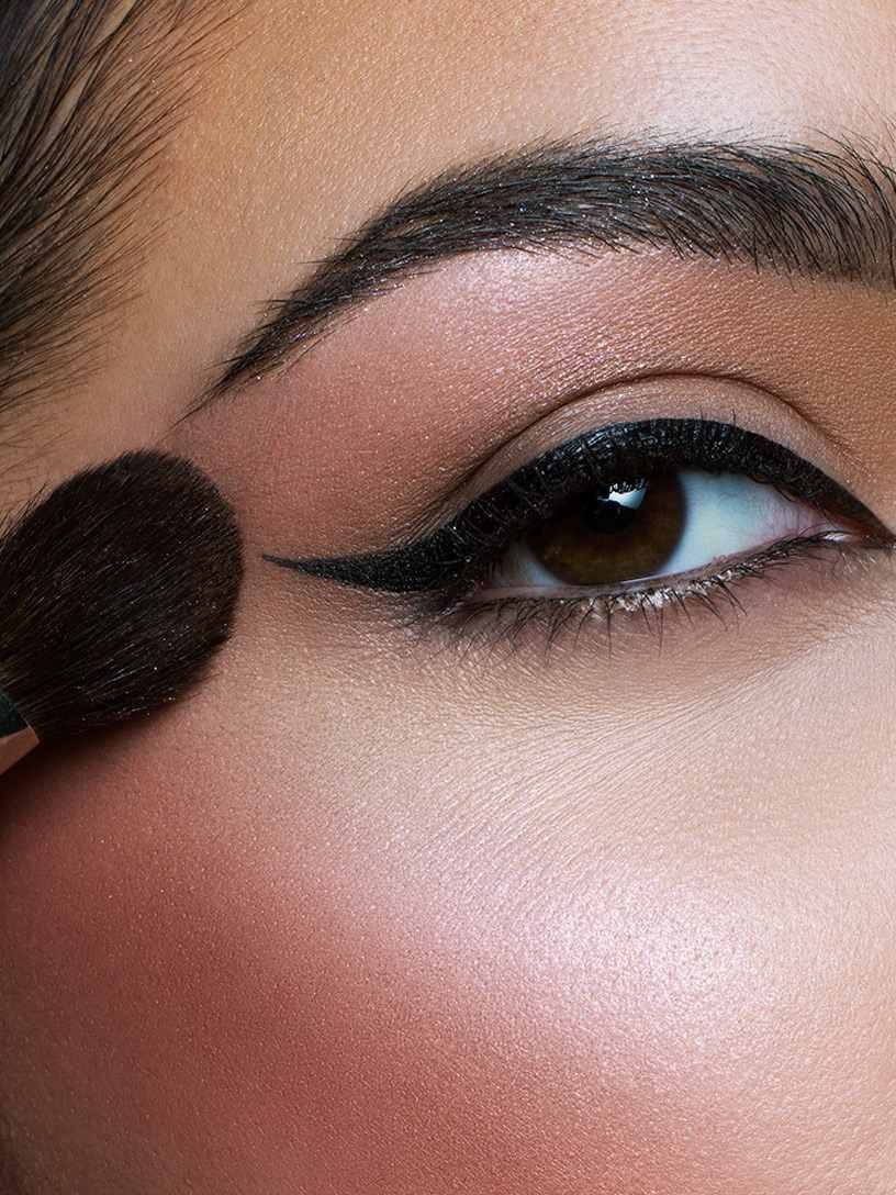 Woman sweeping blush towards brow bones